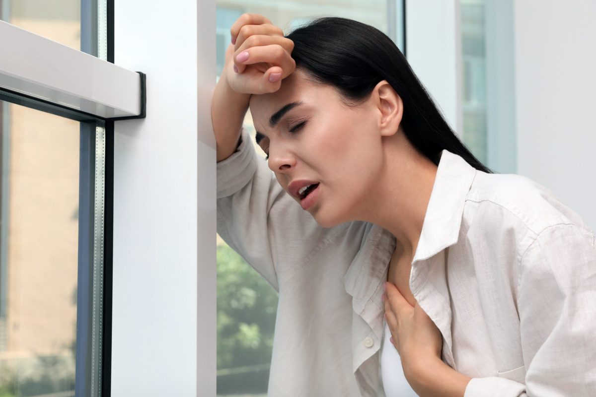 Young,woman,suffering,from,breathing,problem,near,window,indoors